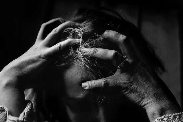 زنی که از افسردگی رنج میبرد و درحال چنگ زدن به سر و موهای خود است ، از چهره ی او ناراحتی و غم پیداست 