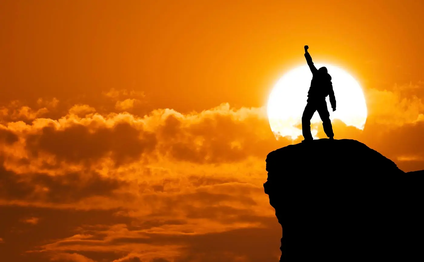 فردی که بالای کوه ایستاده است و با تلاش کردن موفق شده به چیزی که میخواهد برسد