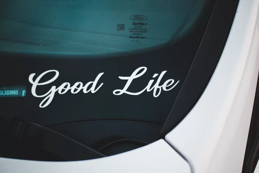 تصویری از پشت شیشه یک ماشین که زندگی خوب با برچسب چاپ شده است