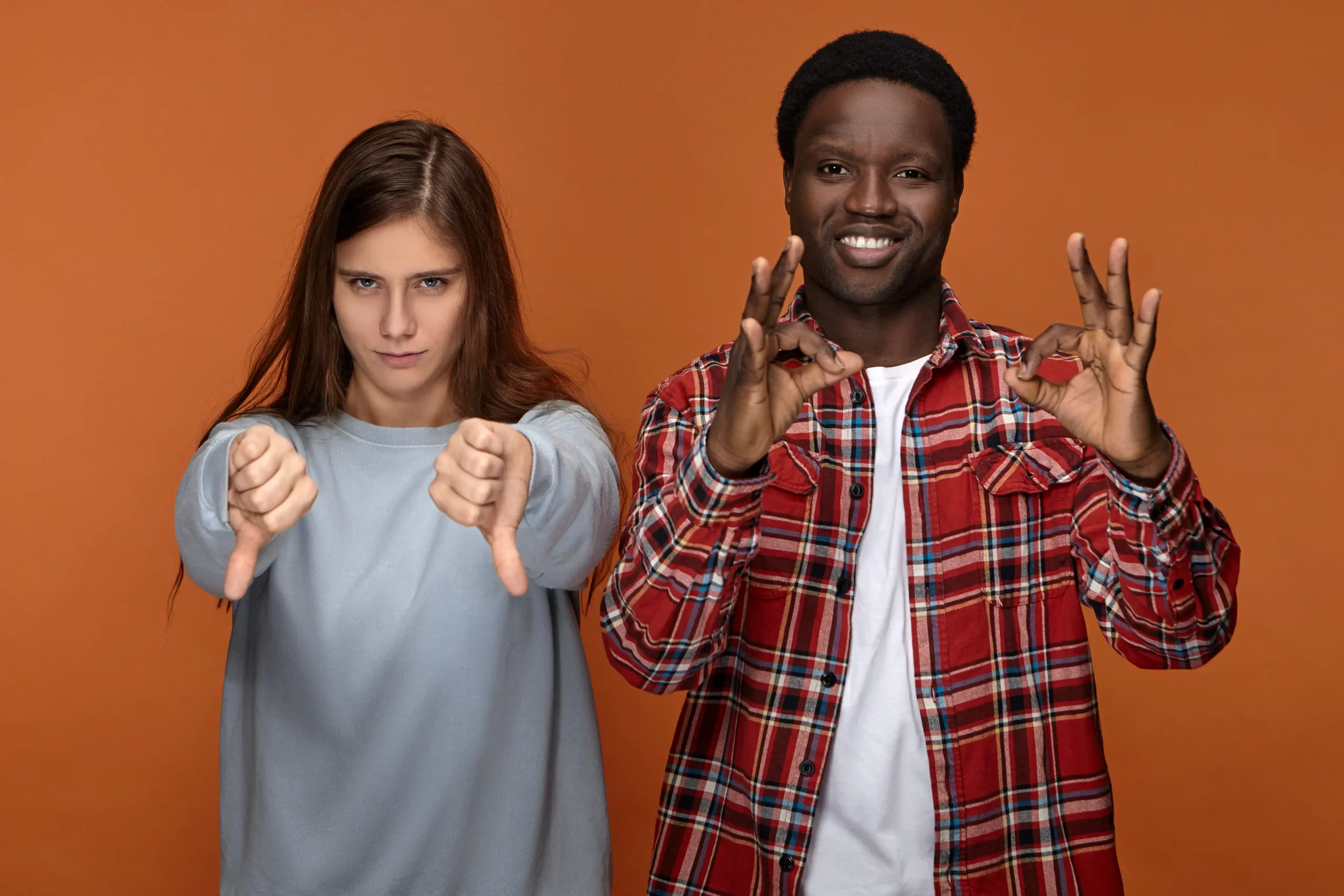 دو فرد سیاه و سفید پوست که در کنار هم قرار دارند و با دستانشان علامت هایی را نشان میدهند