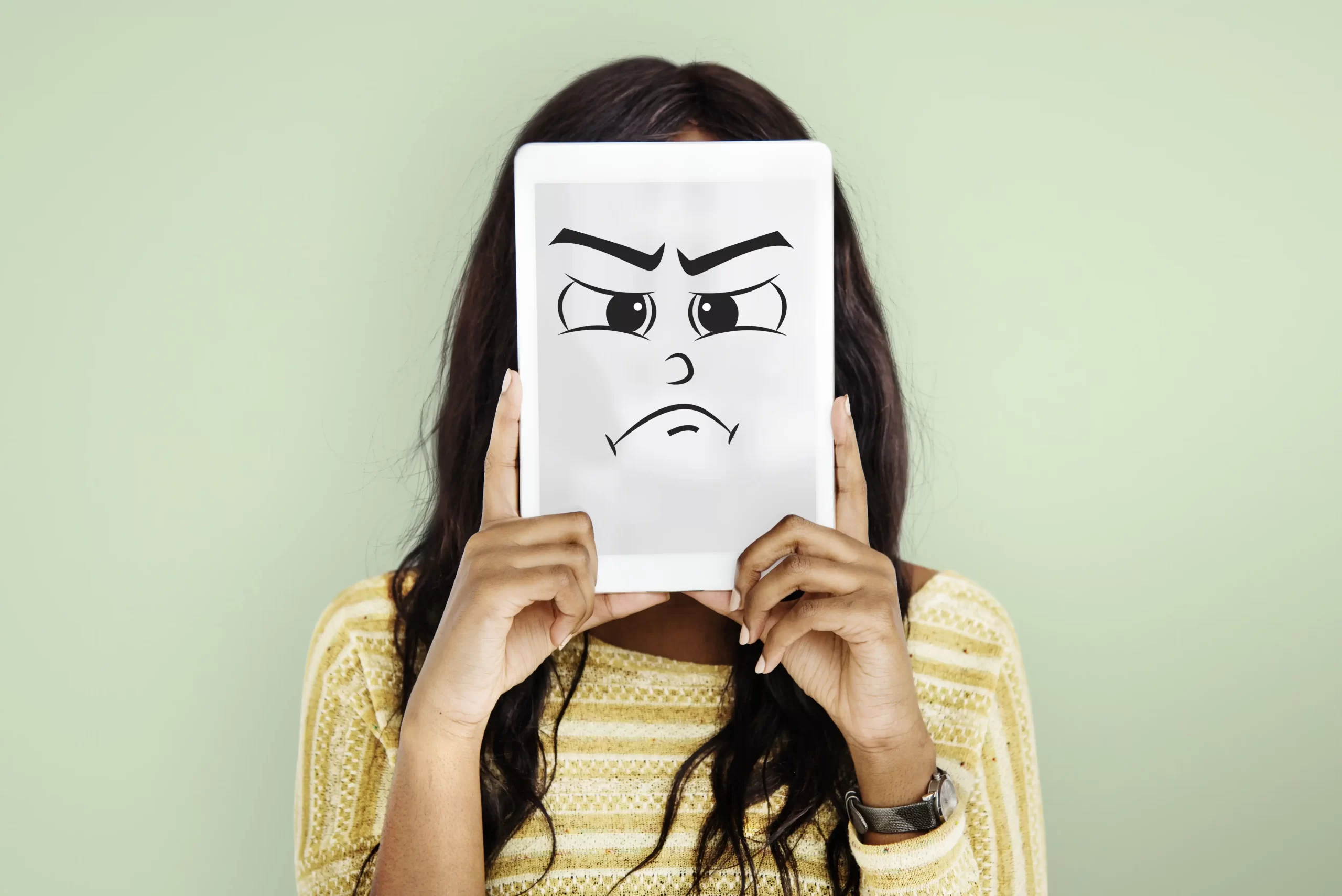در این عکس، یک زن با تابلو سفیدی که بر روی ان صورت ناراحتی که شیده است در دست دارد که تابلو را جلوی صورت خود نگه داشته است
